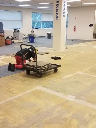Adma Biologics installer removing old carpet tile from subfloor