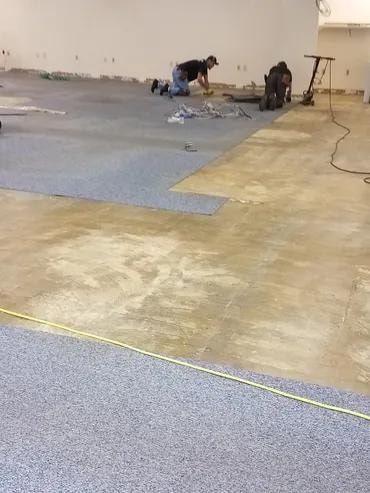 Adma Biologics crew laying new carpet tile on prepared subfloor